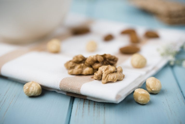 Scattered nuts, dried fruits and whole foods on a light background.